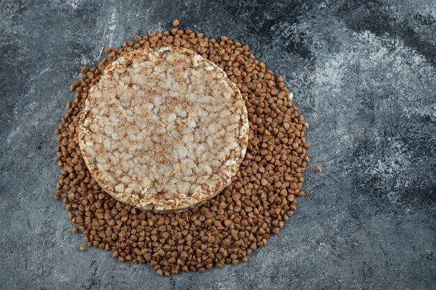 Bolo de arroz simples e trigo sarraceno cru na superfície de mármore