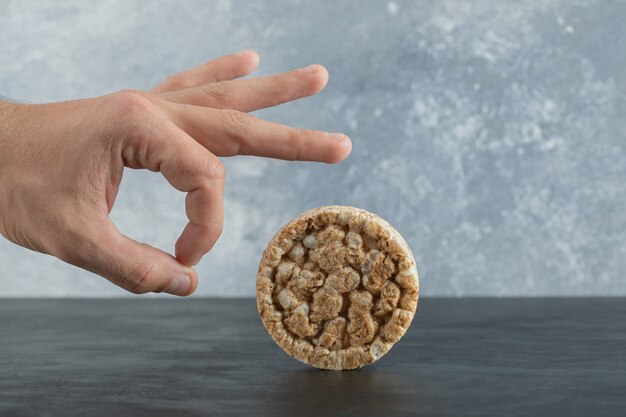 Bolo de arroz tufado e mão masculina em superfície cinza