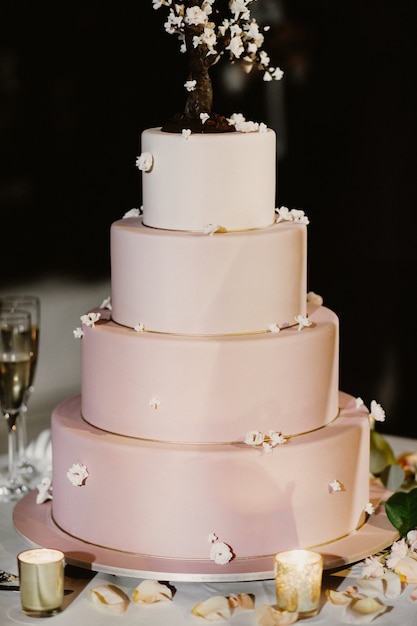 Foto grátis bolo de casamento rosa decorado com velas e pétalas de rosa