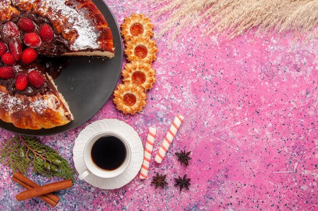 Bolo de chocolate de morango com vista superior e uma xícara de chá na superfície rosa