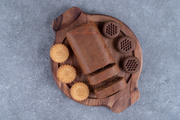 Bolo de chocolate e biscoitos no prato de madeira