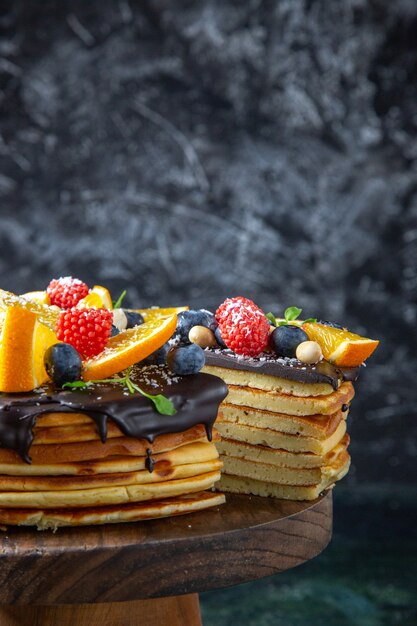 Bolo de chocolate gostoso de frente com frutas na parede escura