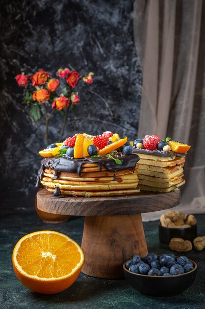 Bolo de chocolate gostoso de frente com frutas na parede escura