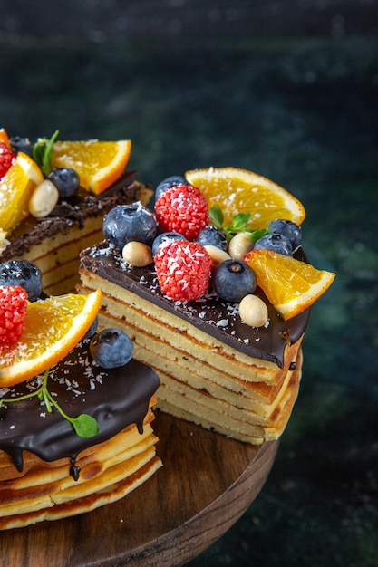 Bolo de chocolate gostoso de frente com frutas na parede escura