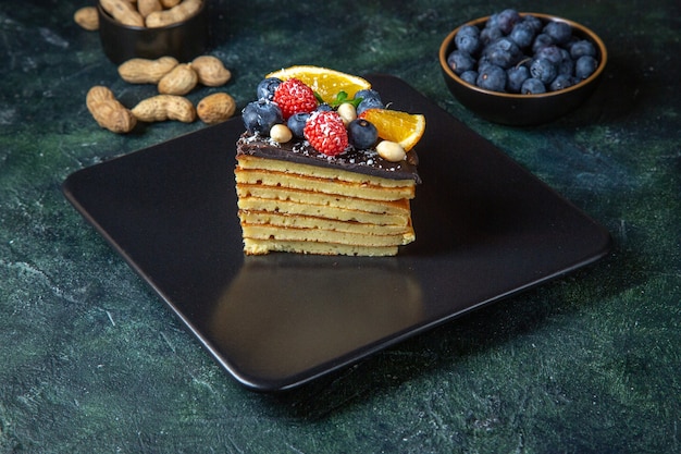 Bolo de chocolate gostoso de frente com frutas na parede escura