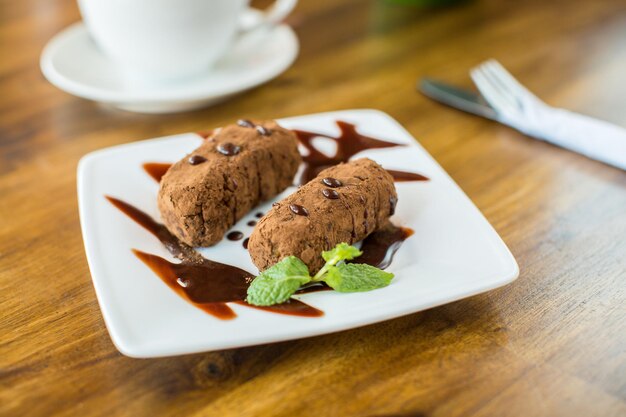 Bolo de chocolate kartoshka e cappuccino em uma mesa de madeira