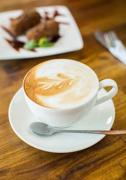 Bolo de chocolate kartoshka e cappuccino em uma mesa de madeira