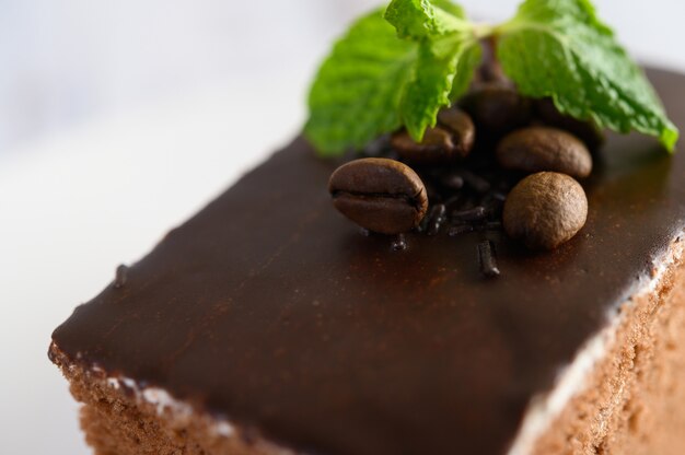 Bolo de chocolate num prato branco com grãos de café em uma mesa de madeira