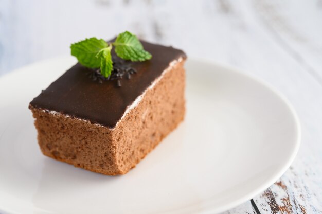 Bolo de chocolate num prato branco sobre uma mesa de madeira.