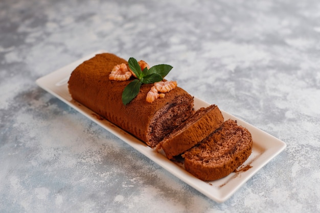 Bolo de chocolate roll com cacau em pó na chapa branca, vista superior