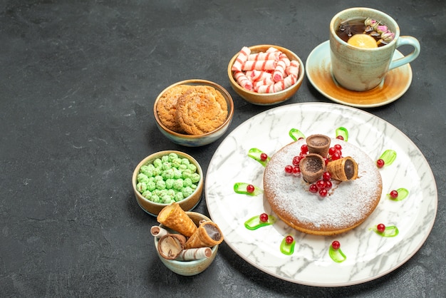 Bolo de doces com frutas vermelhas uma xícara de chá biscoitos doces waffles