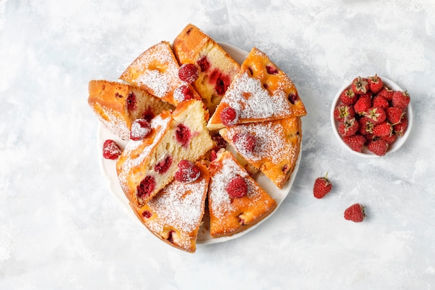 Bolo de framboesa com açúcar em pó e framboesas frescas em uma luz. Sobremesa de verão berry.