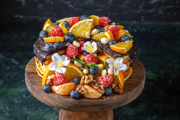 Bolo de frutas delicioso com calda de chocolate em mesa redonda de madeira escura