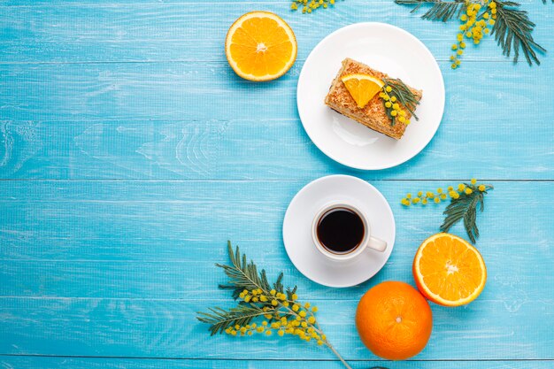 Bolo de laranja decorado com fatias de laranja frescas e flores de mimosa na luz