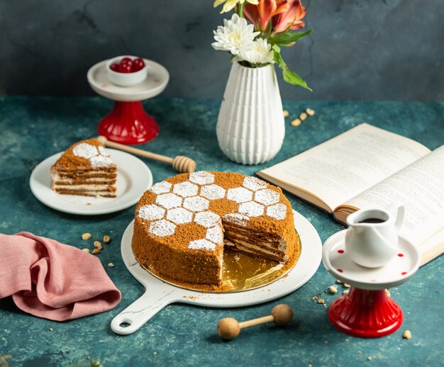 Bolo de mel fatiado, decorado com granulado de pó de açúcar em forma de colmeia de abelhas