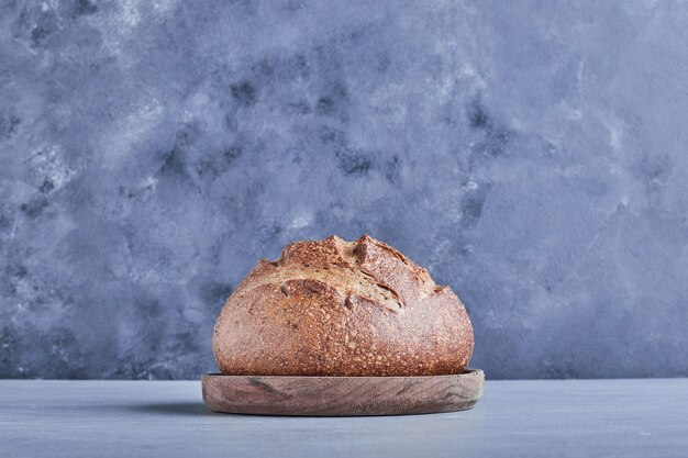 Bolo de pão redondo feito à mão na bandeja de trigo, vista lateral.