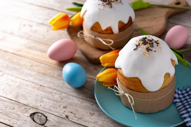 Bolo de Páscoa tradicional, ovos coloridos e tulipas na mesa de madeira