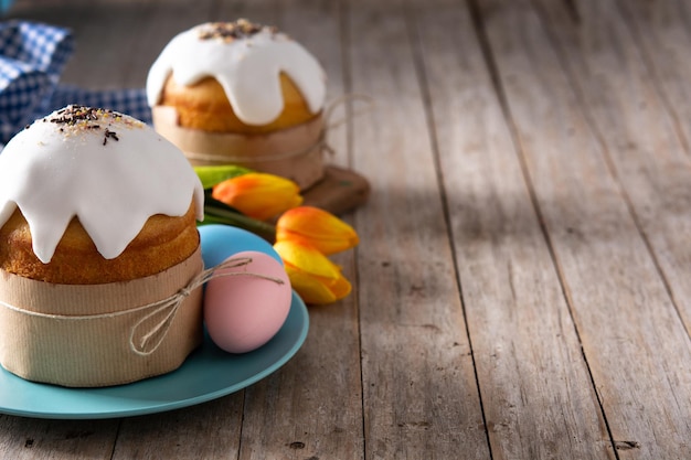 Bolo de Páscoa tradicional, ovos coloridos e tulipas na mesa de madeira.