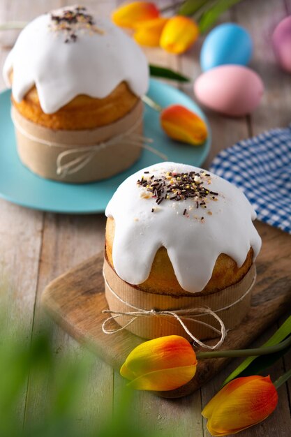 Bolo de Páscoa tradicional, ovos coloridos e tulipas na mesa de madeira