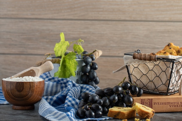 Bolo de passas, uvas e tigela de farinha na mesa de mármore