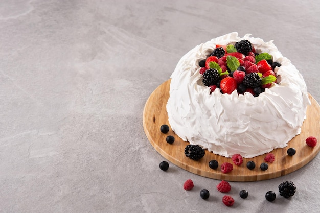 Bolo de Pavlova delicioso com cobertura de merengue e frutas frescas em pedra cinza