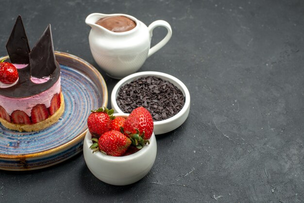 Bolo de queijo delicioso com morango e chocolate no prato tigelas com morangos de chocolate chocolate escuro no fundo escuro isolado.