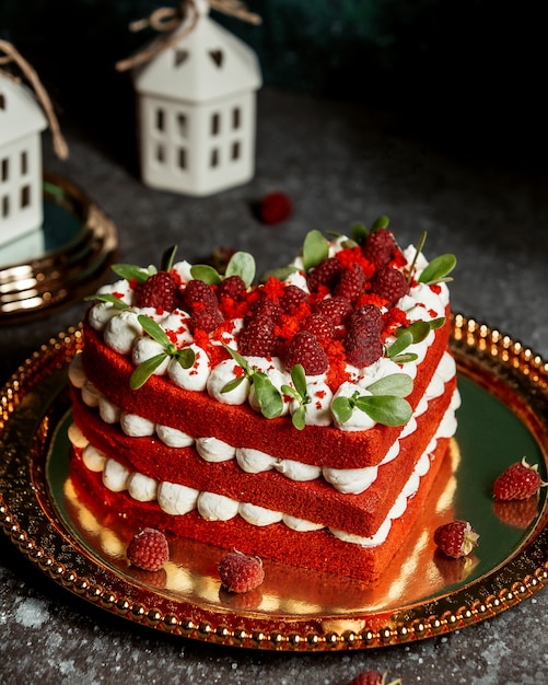 Bolo de veludo vermelho em forma de coração, decorado com framboesas e folhas de hortelã