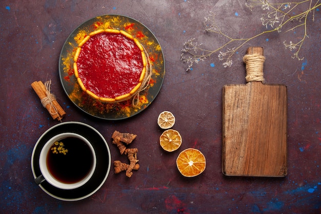 Bolo delicioso com creme vermelho e uma xícara de café na mesa escura de cima