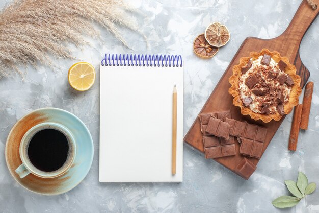 Bolo pequeno cremoso com barras de chocolate, chá e canela na mesa leve, bolo doce açúcar chocolate