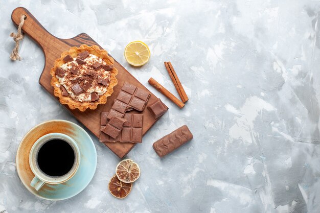 Bolo pequeno cremoso com barras de chocolate e chá de canela em mesa leve bolo doce açúcar creme de chocolate