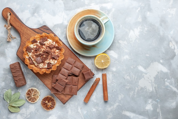 Bolo pequeno de creme com barras de chocolate e chá na mesa leve bolo doce com creme de chocolate