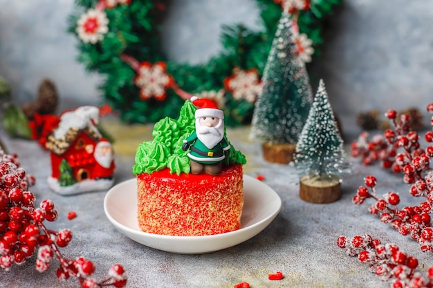 Bolo pequeno de Natal decorado com doces figuras de árvore de Natal, Papai Noel e velas.