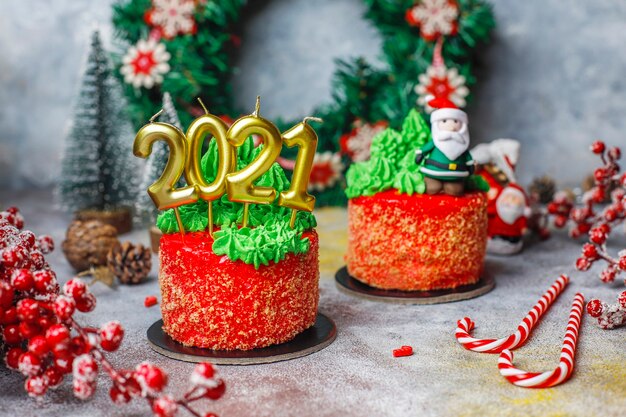 Bolo pequeno de Natal decorado com doces figuras de árvore de Natal, Papai Noel e velas.