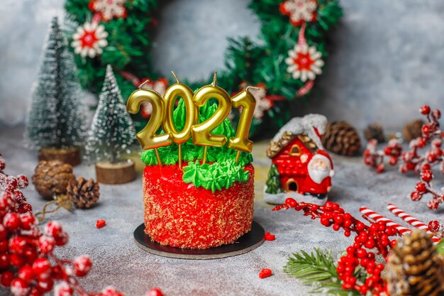 Bolo pequeno de Natal decorado com doces figuras de árvore de Natal, Papai Noel e velas.