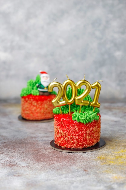 Bolo pequeno de natal decorado com doces figuras de árvore de natal, papai noel e velas. Foto gratuita
