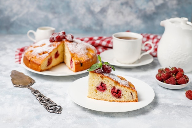 Bolo simples com açúcar de confeiteiro e framboesas frescas em uma luz. Sobremesa de verão berry.