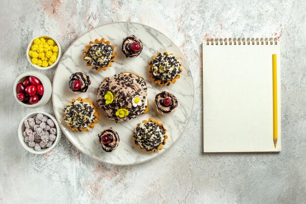 Bolos cremosos deliciosos com doces na mesa branca, bolo de chá, biscoito doce, creme de aniversário