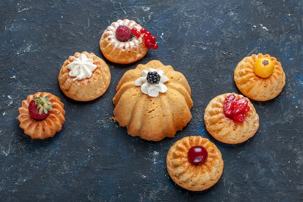 Bolos deliciosos diferentes assados com creme e frutas vermelhas no escuro, baga bolo de biscoito doce