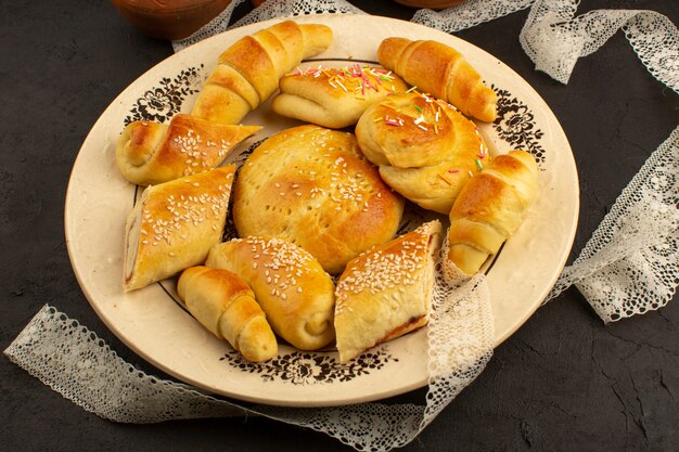 bolos e croissants de vista superior dentro de chapa branca no escuro