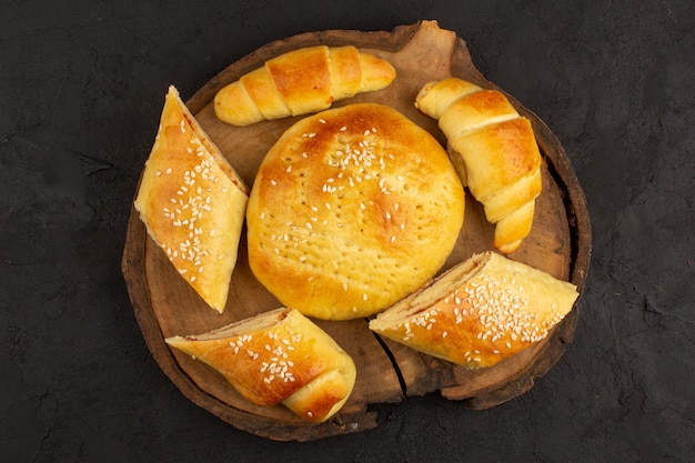 Foto grátis bolos e croissants de vista superior na mesa marrom e escuro