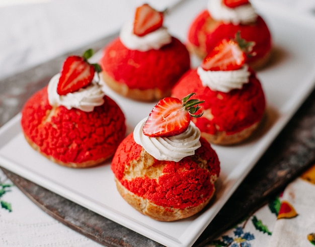 Bolos redondos de morango gostoso delicioso com morangos fatiados de creme dentro de chapa branca