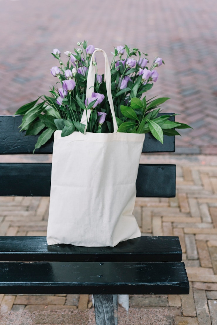 Foto grátis bolsa de algodão branco com belas flores roxo eustoma no banco preto