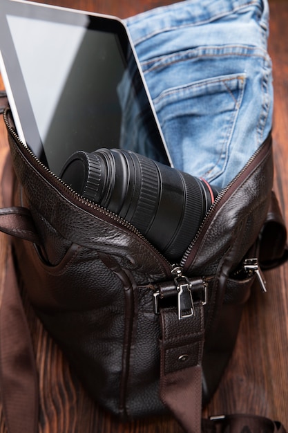 Foto grátis bolsa de couro embalada com jeans, câmera e tablet