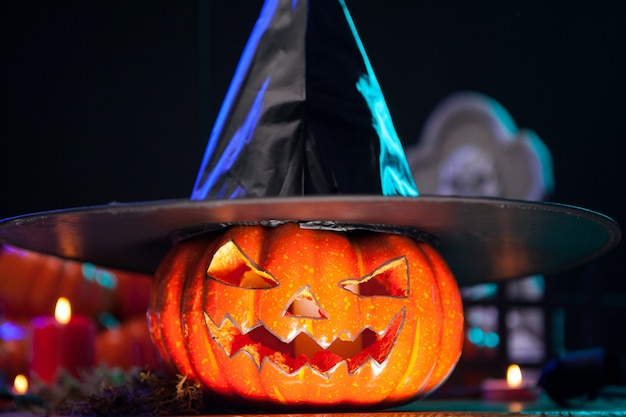 Foto grátis bombeamento vicioso com uma cara assustadora usando um chapéu de bruxa na festa de halloween. bombeamento de laranja. decoração de halloween.