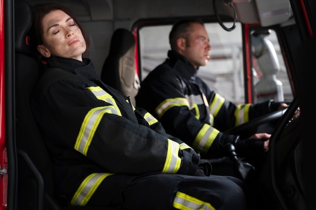 Bombeiro masculino e feminino na estação em caminhão de bombeiros