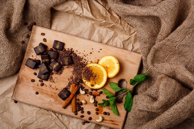 Bombons de chocolate laranja hortelã canela e nozes na mesa de madeira.