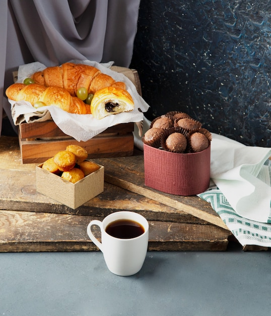 Bombons, muffins, croissants e uma xícara de café