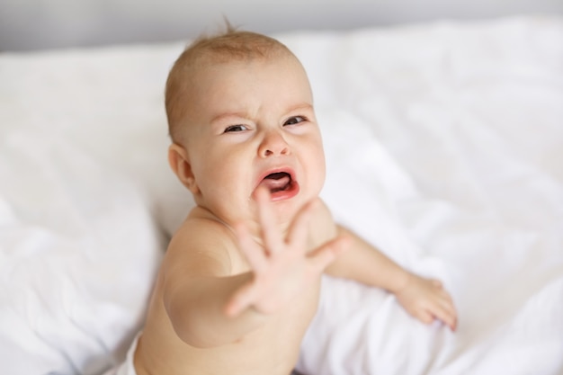 Bonita bebê pequeno bonito mulher chorando deitado com a mãe na cama em casa.