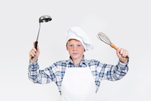 Bonita criança segurando ferramentas de cozinha