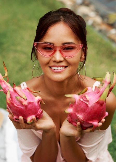 Bonita mulher asiática segurando frutas dragão-de-rosa nas mãos
